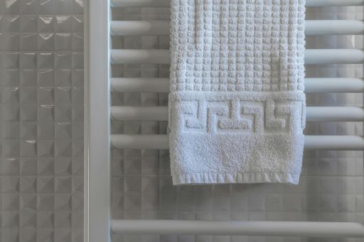White towel on a radiator in a modern, minimalist bathroom with tiled walls.