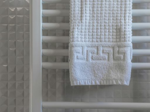 White towel on a radiator in a modern, minimalist bathroom with tiled walls.