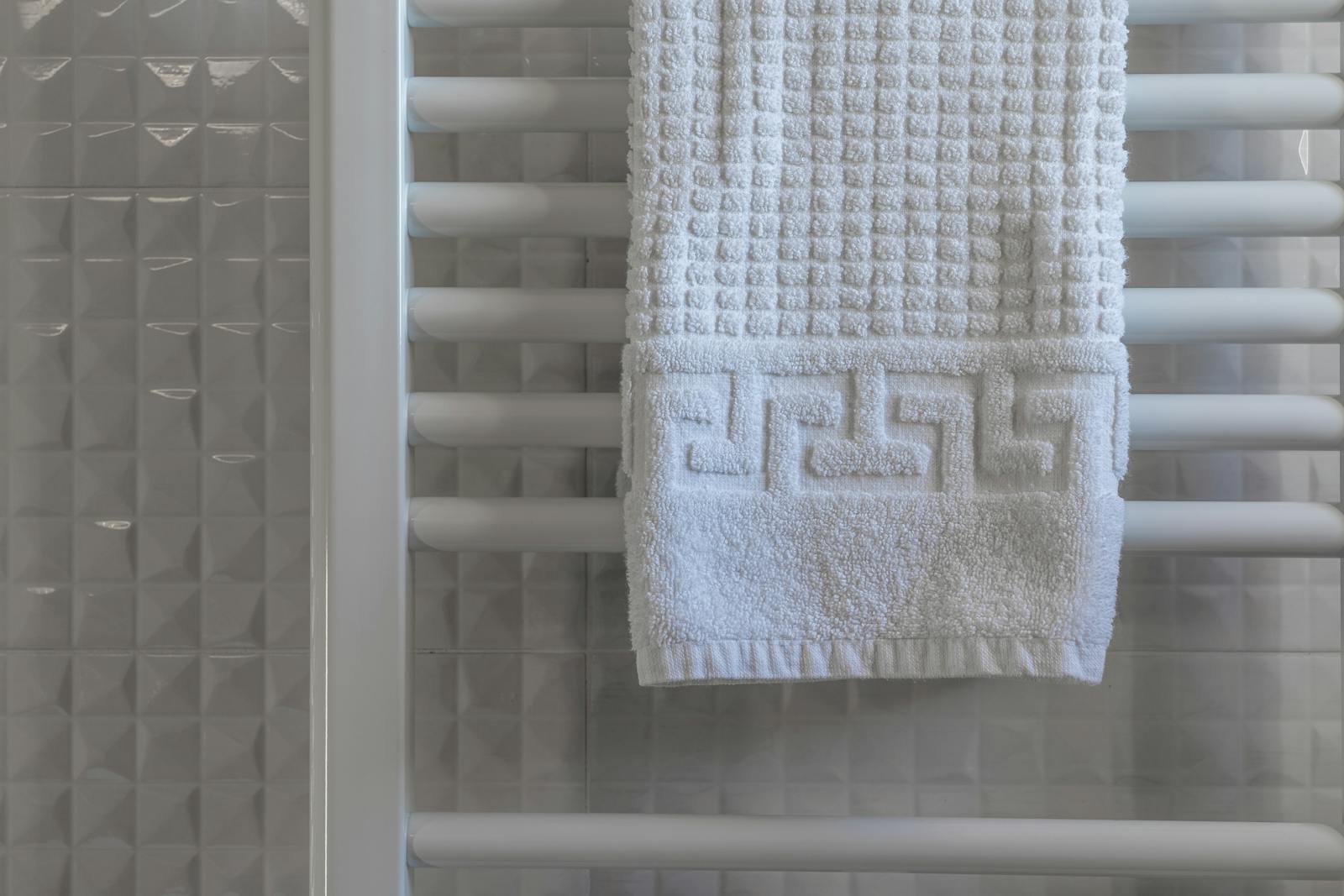 White towel on a radiator in a modern, minimalist bathroom with tiled walls.
