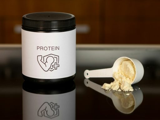 a container of protein powder next to a spoon