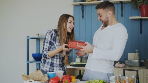 Woman gives man a gift in the kitchen
