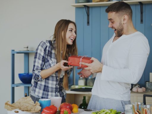 Woman gives man a gift in the kitchen