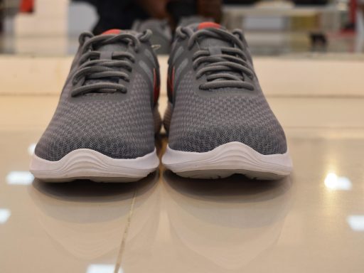 Verschillende sportschoenen voor mannen op een gymvloer naast trainingsmateriaal