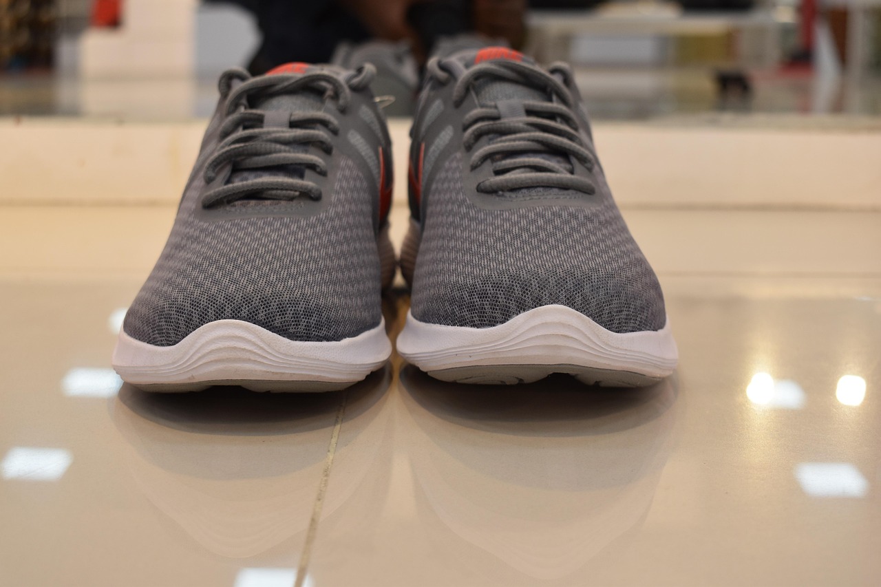 Verschillende sportschoenen voor mannen op een gymvloer naast trainingsmateriaal